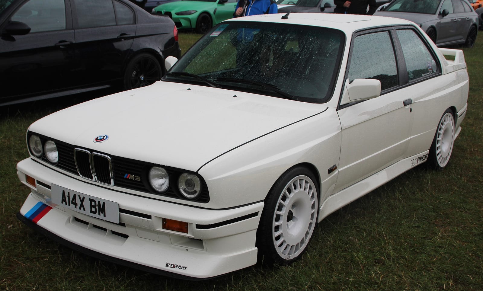 Λευκή BMW M3 E30 σε τριών τετάρτων όψη, με τα φαρδιά φτερά και τον πίσω αεροδυναμικό πρόβολο