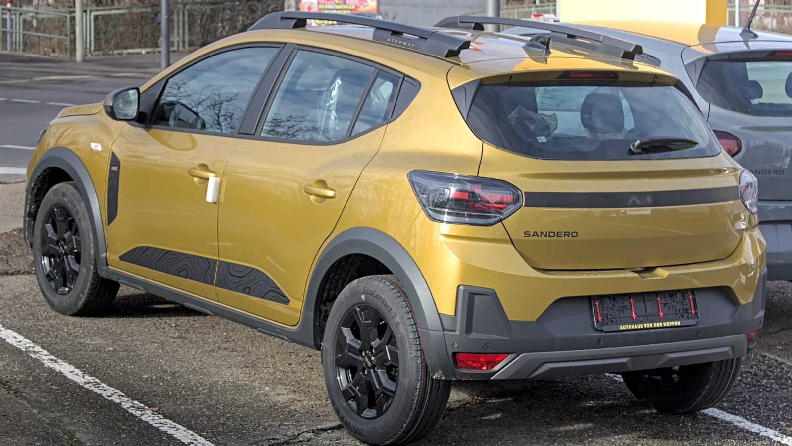 Κίτρινο Dacia Sandero Stepway του 2026, σε πίσω τριτέταρτη όψη, σε πάρκινγκ στη Στουτγάρδη