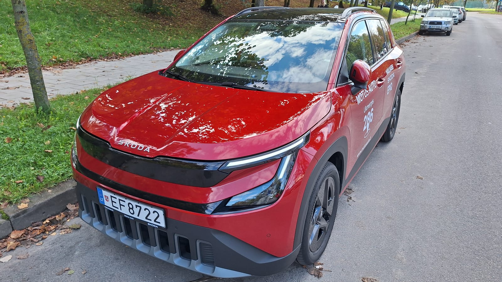 Κόκκινο Skoda Epiq σε μπροστινή τριτέταρτη όψη, σταθμευμένο σε δεντρόφυτο δρόμο